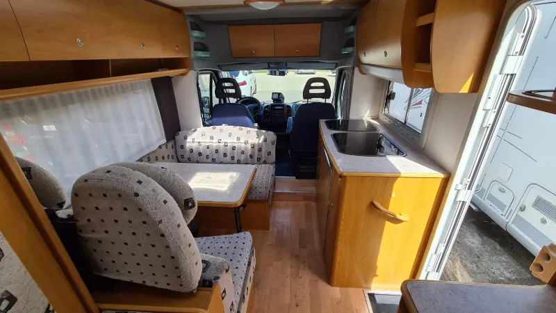 Innenraum eines Wohnmobils mit Sitzgruppe, Küchenzeile und Blick ins Fahrerhaus – Beispiel für Gebrauchtwohnmobil beim Ankauf